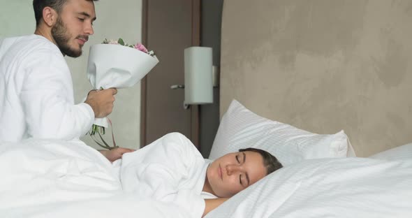 Man Wakes Up Girlfriend and Presents Bouquet in Hotel Room