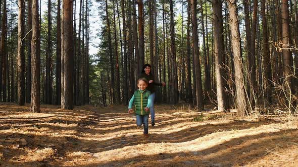 A Young Mother Plays with Her Son, Catching Up with Him. The Child Runs Away From His Mother. Happy alt