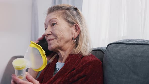 Elderly Woman Using Oxygen Inhaler While Having a Phone Call alt