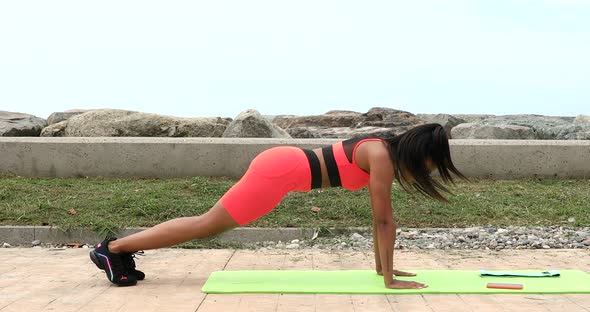 Sporty woman is planking outdoor during fitness session.
