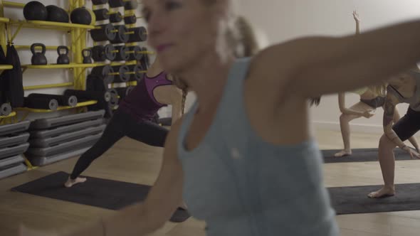 Group of adult women doing yoga exercises in gym