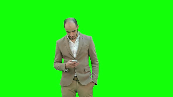 Business Man Walks in Texting on the Phone on a Green Screen, Chroma Key alt
