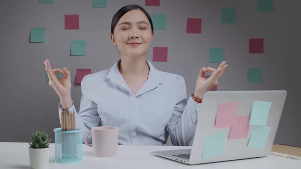 Asian woman calms down, breathes deeply with meditating holding her hands in yoga gesture