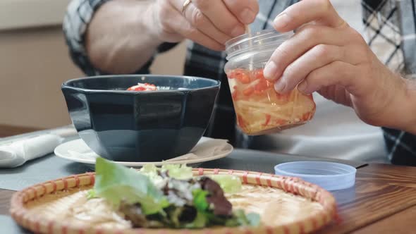 A Man Puts Seasonings and Pepper in a Readymade Noodle Soup in a Bowl