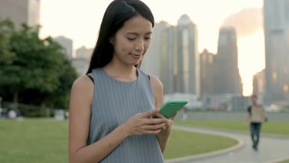 Business woman use of cellphone under sunset at hong kong alt