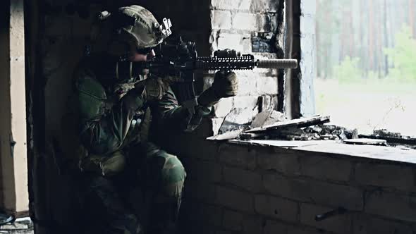Soldier in Camouflage with a Military Weapon Aiming Through the Rifle Sight Through the Window of an alt