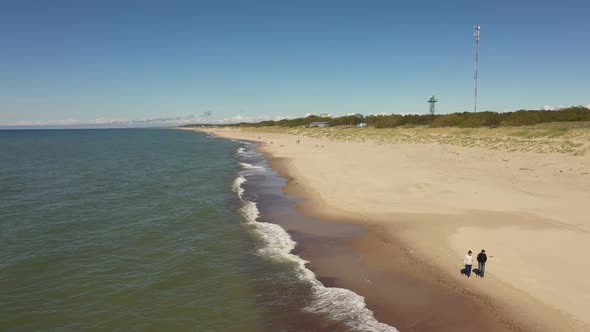 Two women are walking along the beach, view from a drone alt