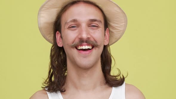 Longhaired Guy with Beautiful Smile in Beige Hat Posing Over Yellow Background Closeup alt