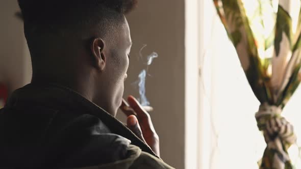 Rear View of Man Seen Standing at Window and Smoking alt