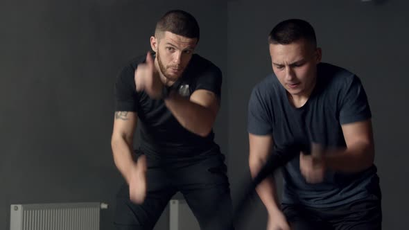 Young Man with Instructor Using Battle Ropes in Gym