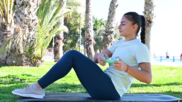 Young woman do sport on the grass in the park among the palm trees