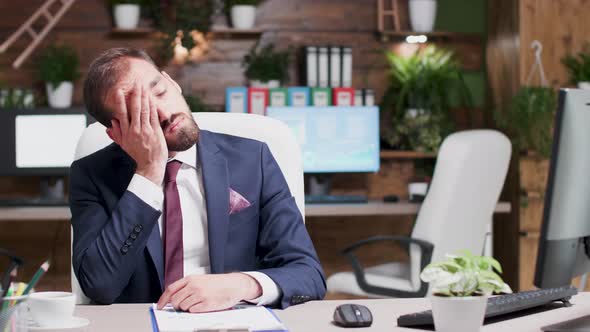 Exhausted and Overworked Businessman Looking at Clipboard with Sales Data alt