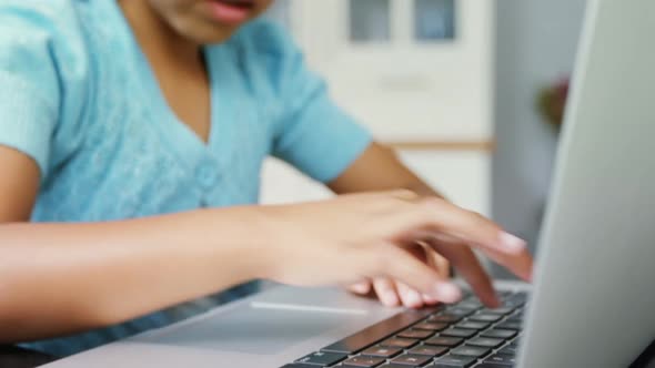 Girl using laptop in kitchen 4k alt
