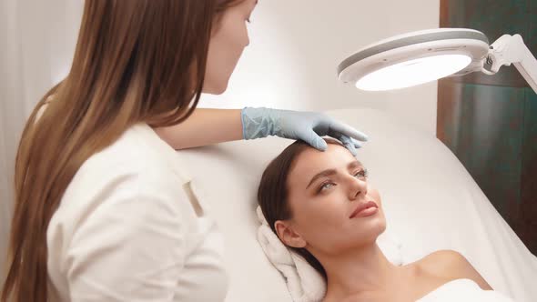 Cosmetologist Cheking Female Skin on Face at Beauty Clinic alt