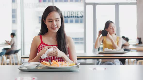 Asian woman sitting separated in restaurant eating food .keep social distance alt