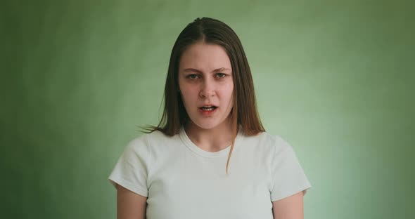 Sad Angry Lady Holds Back Tears Looking Into Camera on Green alt
