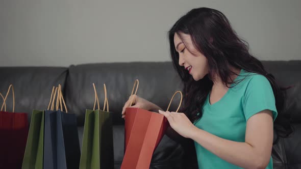 happy woman opening shopping bags in the living room