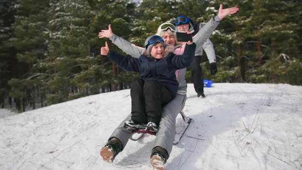 Happy Childhood with Grandparents in Winter Forest Grandson with Grandma Sledding Down Hill and alt