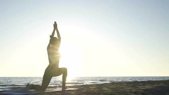 Young Caucasian Woman Practicing Yoga on the Beach Near Calm Sea