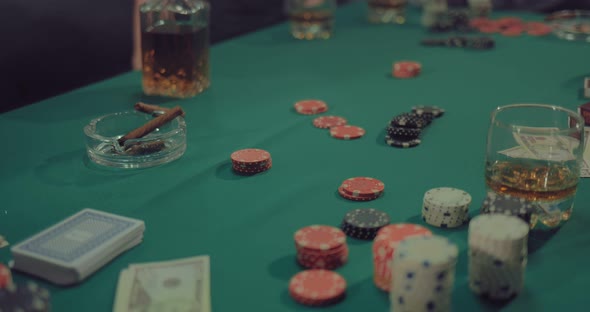 On a Green Gaming Table are Chips Money Cards and Cigars of Players alt