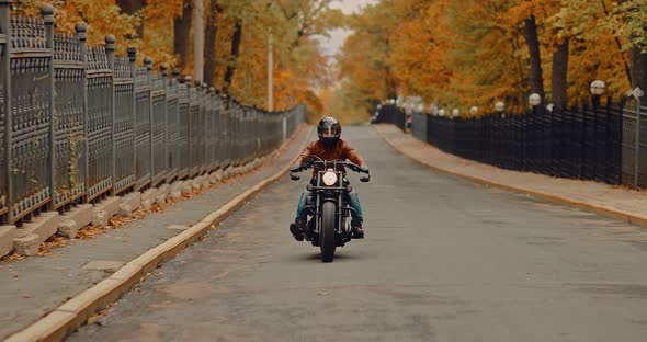 Cool Motorcyclist Quickly Rides on an Asphalt Road. Autumn Walk on a Cool Bike. alt