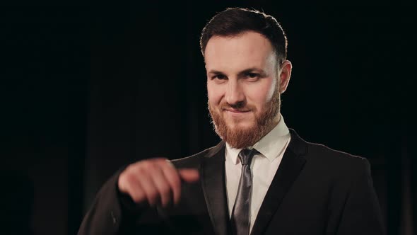 A Man in a Suit is Standing on Stage and Looking at the Camera alt