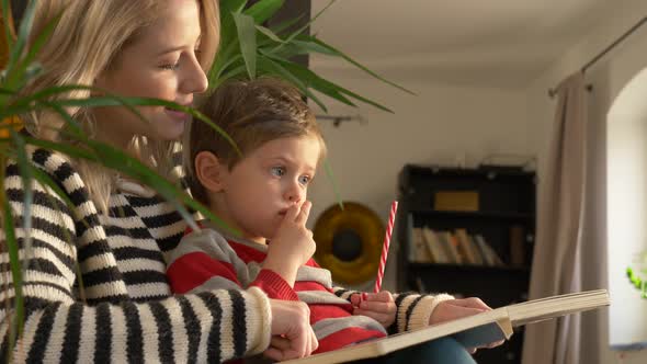 mom tells a story to her son while sitting in armchair at home alt