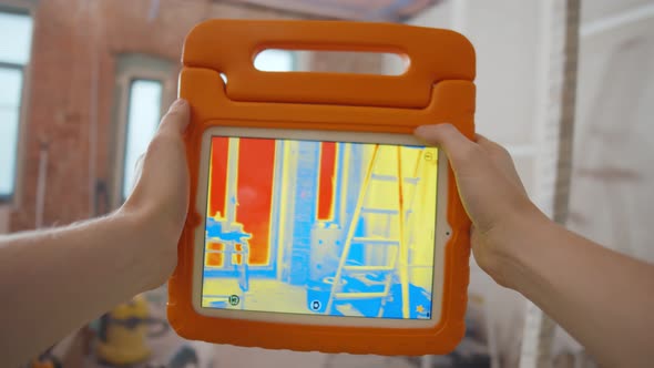 Close Up of Person Detecting Heat Loss Inside House Using Infrared Thermal Camera alt