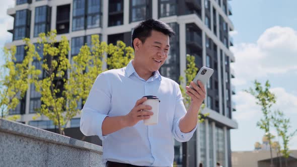 Chinese Business Man Reading Good News on Mobile Phone alt