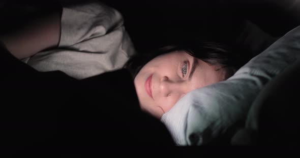 Young Woman Browsing Internet, Use Smart Phone On Bed At Night. Low Angle. alt