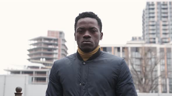 Portrait of a Sad African American Man Standing Near the Office Building and Looking at Camera alt