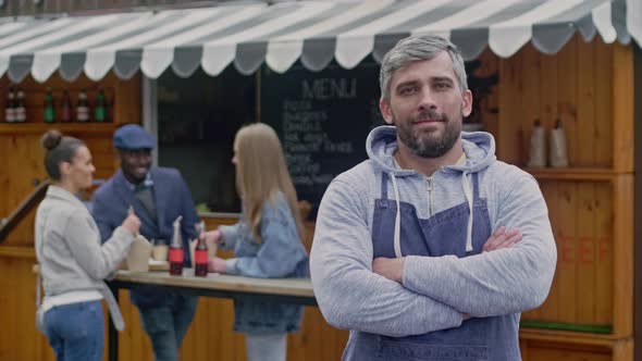 Smiling street cafe's owner standing outside