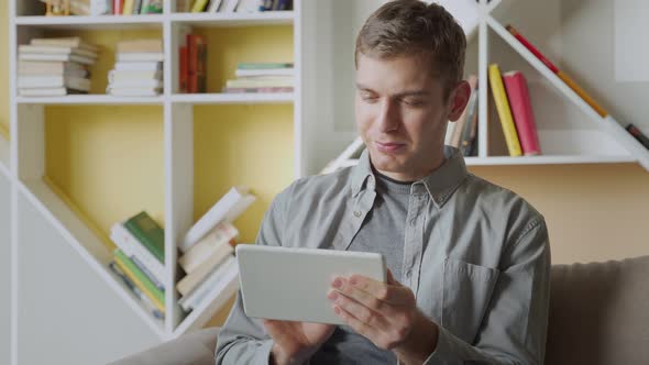 Smiling Man Using Tablet Relaxing on Sofa in Modern office.Concept of Young Business People Working alt