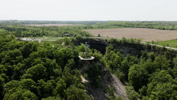 Aerial orbiting shot showing cross landmark in front of Devil's Punch Bowl in summer. Ontario,Canada alt