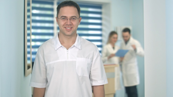 Smiling male doctor in glasses looking at camera while