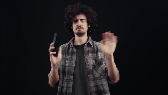 The Irritated and Frowning Young Man Looks at the Phone Screen Receives a Message That Upsets Him alt