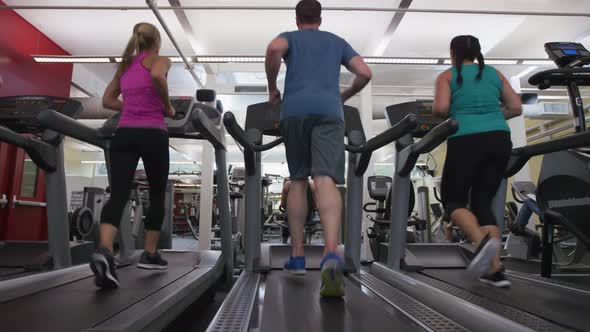 People running on treadmills at gym