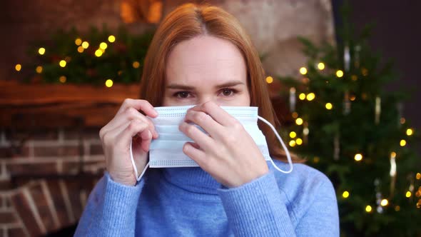 A Woman Wears a Protective Mask on Her Face Before a Christmas Tree Party alt