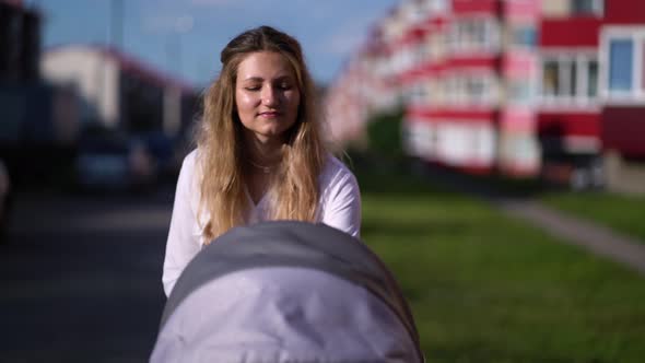 Woman of Caucasian Appearance Walking in a Newborn Baby Outdoors