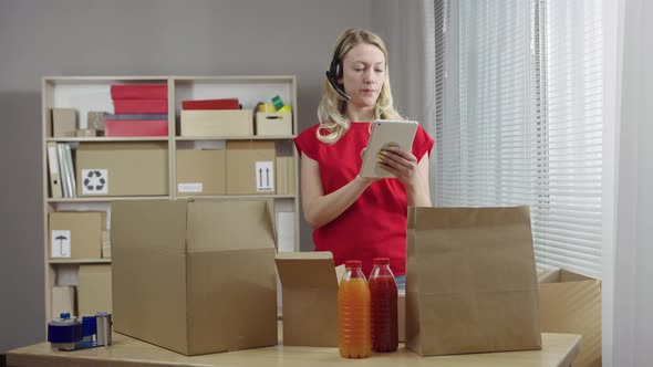 Warehouse Worker is Working in an Office Room Against Background of Boxes alt