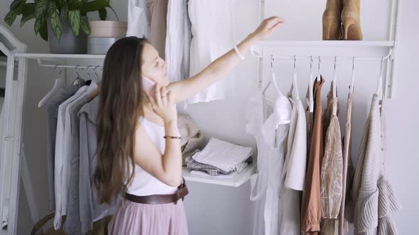 Woman Talks on Phone Choosing Elegant Clothes in Wardrobe