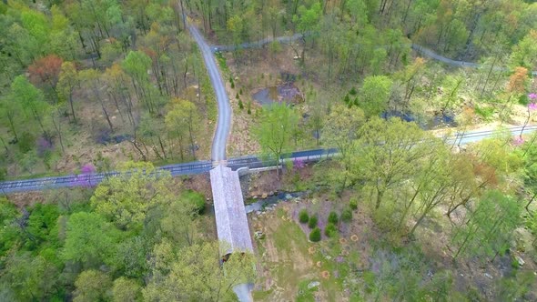 Aerial View of Spring Time Colors of a Forest with a Covered Bridge and Rail Road Track alt