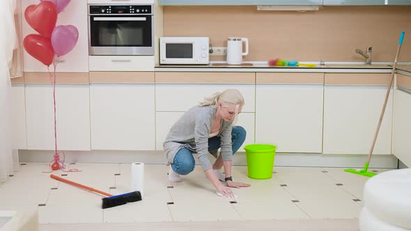 A Young and Beautiful Blonde Is Engaged in Cleaning the Kitchen alt