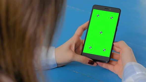 Woman Looking at Black Smartphone with Empty Green Screen - Chroma Key Concept
