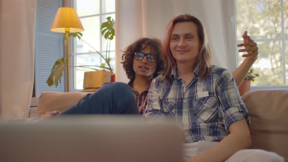 Homosexual Male Couple at Home on Couch Working and Communicating Via Laptop alt