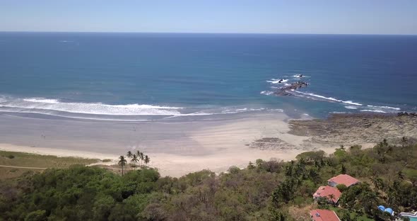 Aerial drone view of the beach, rocks and tide pools in Guiones, Nosara, Costa Rica. alt