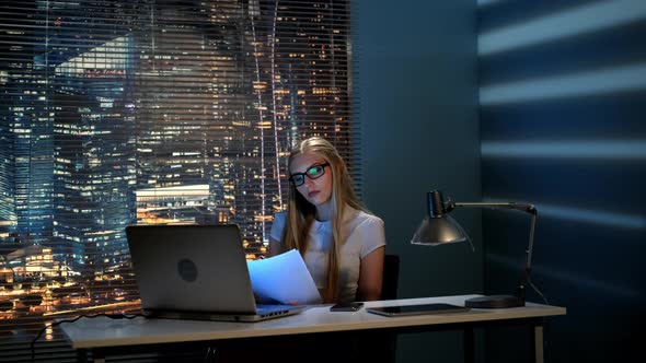Young Female Professor Correcting Her Report Late at Night and Checking Smartphone alt