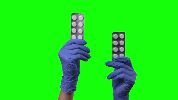 Doctor Shows Pills. Female Hands in Protective Blue Gloves Closeup at Green Screen. alt