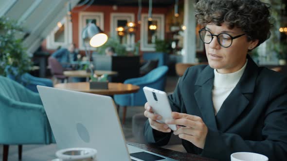 Ambitious Businesswoman Using Laptop Then Answering Phone Call in Cafe alt