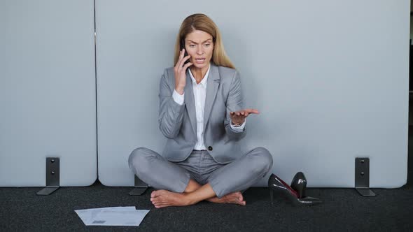 Nervous Tired Businesswoman Talking on the Phone While Sitting on the Floor alt